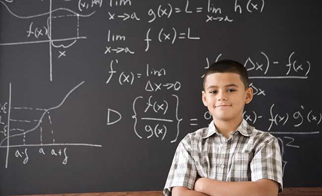 Hispanic boy smiling in front of math formula on blackboard